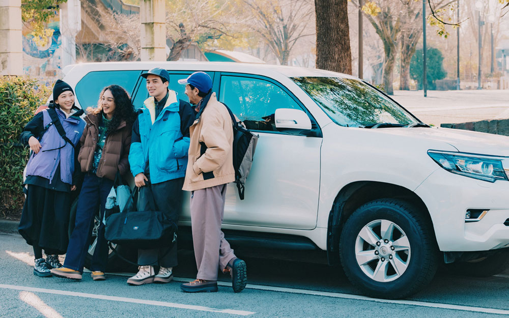 YELLOWTALIL&trade; ICE MAGICをを着用した女性2名と男性2名が、白い車に寄りかかって話している様子