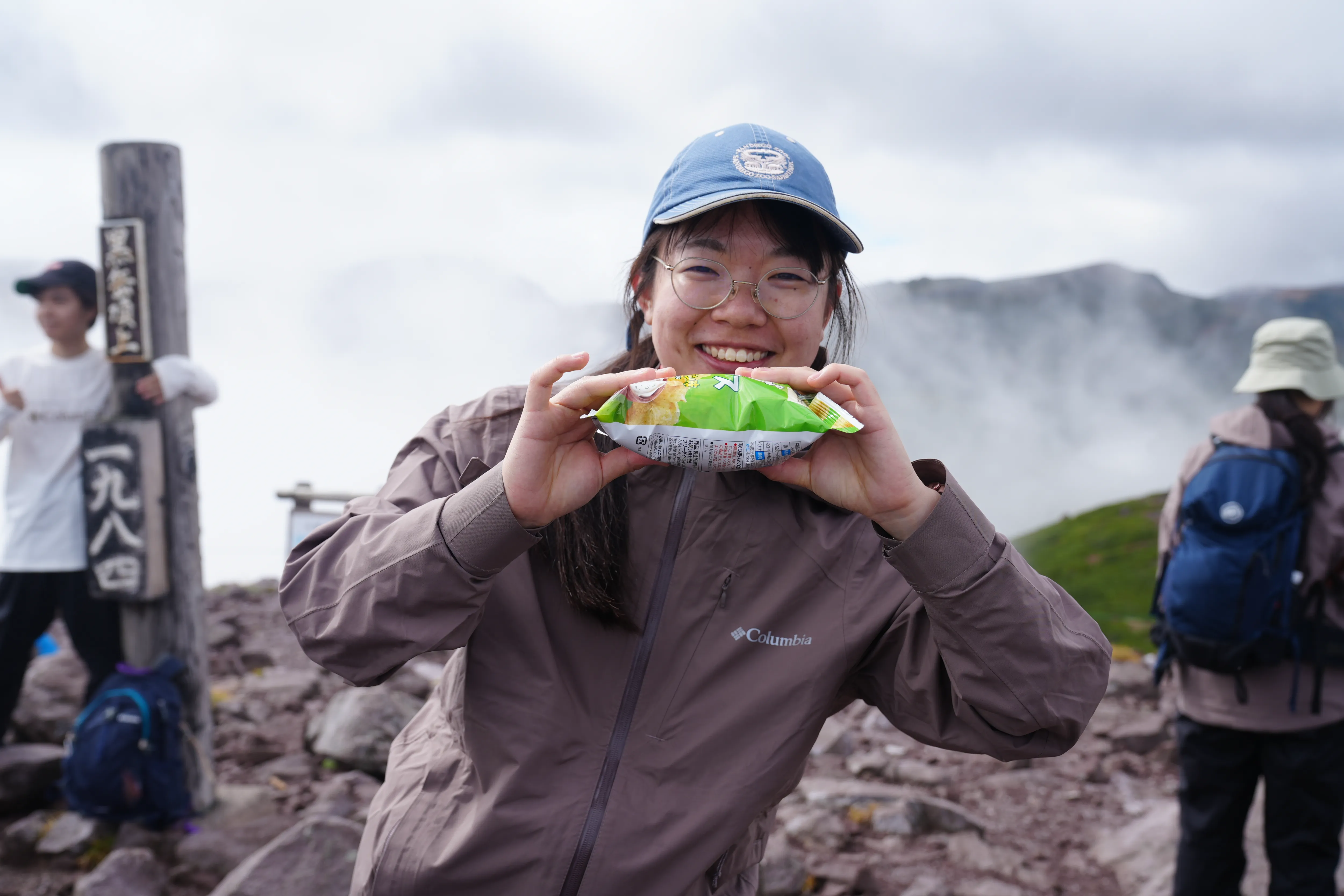 山頂でポテトチップスの袋を確かめる学生